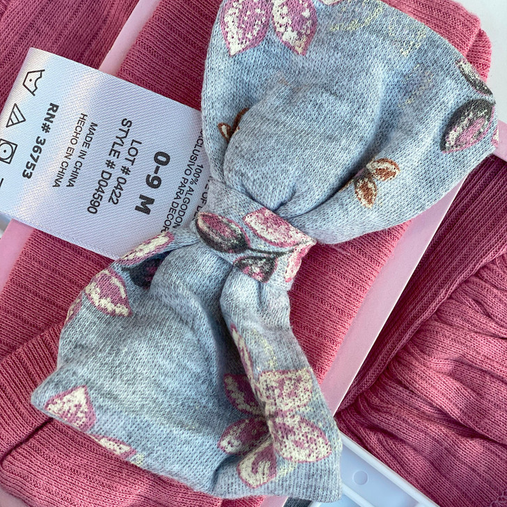 Generic Flower Layette Set 4 Piece, image shows a soft, patterned baby sock with floral design on a pink cloth background.