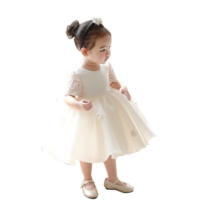 OONA Daisy Dress Ivory White, adorable young girl wearing a white dress with lace sleeves and floral accents, styled with a headband and beige shoes, perfect for special occasions or events.