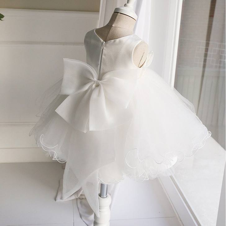 OONA Emma Tulle Bouffant, white tutu dress for girls with a large satin bow at the waist and sleeveless design on a dress form.