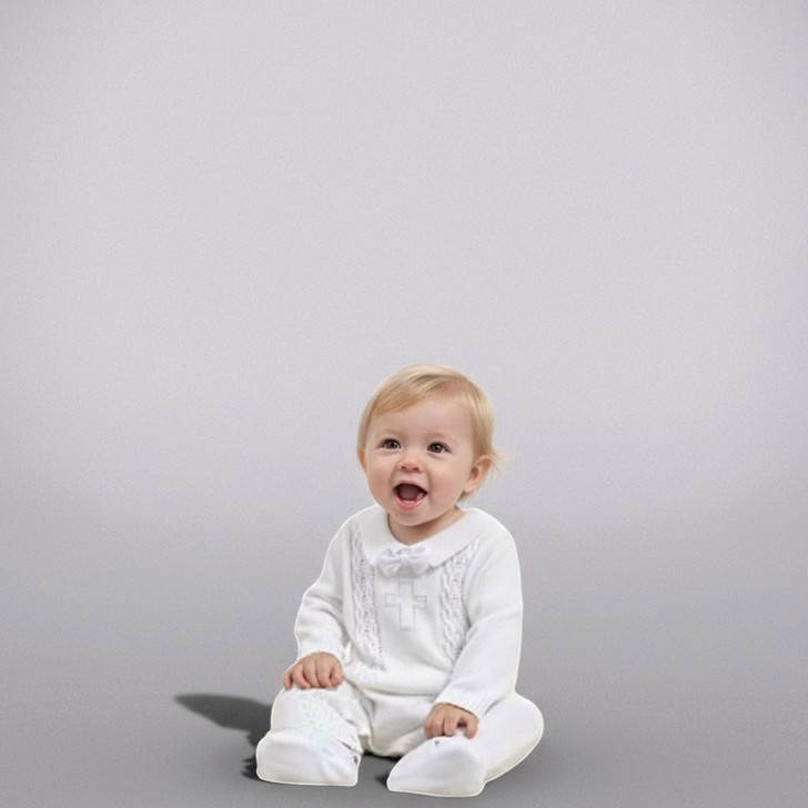 Minnie Me Noah Christening Romper, adorable baby girl wearing a white christening romper with embroidered cross design, sitting on the floor with happy expression.