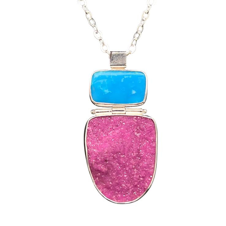 Druzy Cobalto-Calcite Pendant with Blue Persian Turquoise. A rare grouping of natural minerals with intense colors that are completely natural. I cut the pink calcite from a specimen from Congo, Africa. It has small pink sugar-like crystals that are colored by manganese. The blue translucent gemstone comes from Iran’s ancient turquoise mines. Hanging pendant with hinges and sterling silver with an 18”chain.