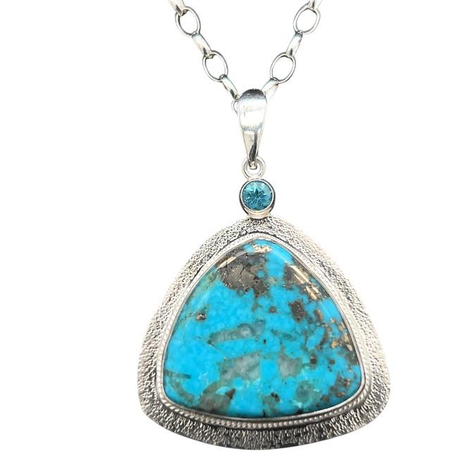 Turquoise & Pyrite Pendant with Apatite accent. I cut this unusual turquoise from Turkey with a triangular shape. It has metallic inclusions of silver colored pyrite. Set in fine silver with accent wire on the border and hand textured background. 18” sterling silver chain included. 1.5”h by 1.5” w.