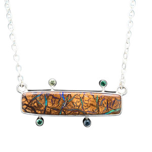 Koroit Opal & Sapphire Pendant. I cut this Australian ironstone Koroit Opal to showcase the seams of precious black opal that filled in the fissures of the host rock. Accented with multi-colored sapphires and emeralds. Fine silver bezel with an 18” sterling silver chain included.