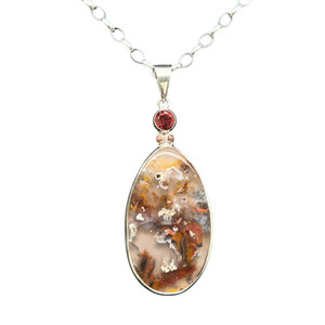 Quartz with Copper Pendant. I cut this rare material from a specimen from Indonesia. The quartz crystal is included with veins of elemental copper that shine in the sun. I cut it in a large teardrop shape. It is set with a unique orange-pink Malaya Garnet that I cut with a ‘Classic’ brilliant design. Accent copper beads are set on sterling silver and 18’ silver chain is included.