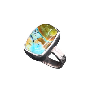 Opalized Wood Ring.
I cut this hefty cushion shaped stone from a piece of petrified wood from Indonesia. This special stone is actually Opal that replaced the wood structure of an ancient log covered by volcanic ash. Look closely and you will see a small vein of raw copper that was deposited in the petrified wood grain. Size 7 set in a fine silver bezel with my signature textured sterling silver ring shank.
