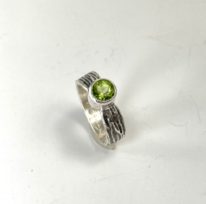 Faceted peridot ring on a bark textured silver band