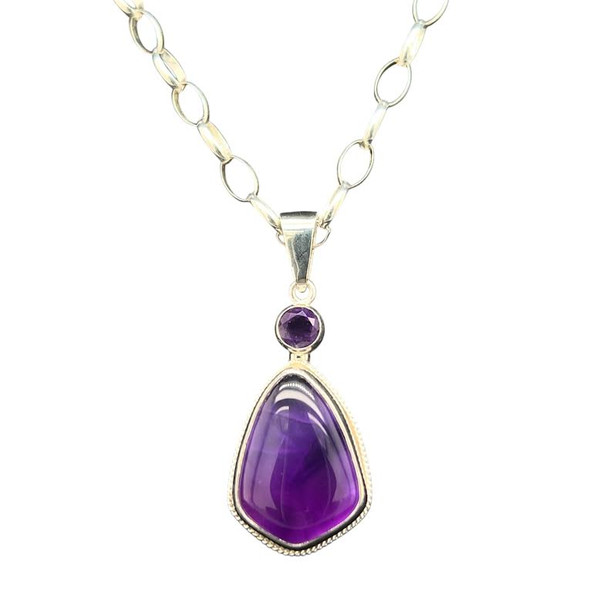Amethyst Pendant.
I cut this large Brazilian Amethyst into a unique shield cut shape inspired by my trip to Vietnam. Set with another accent amethyst stone and a fine silver bezel surrounded by a gallery wire. Comes with 18” silver chain and clasp.