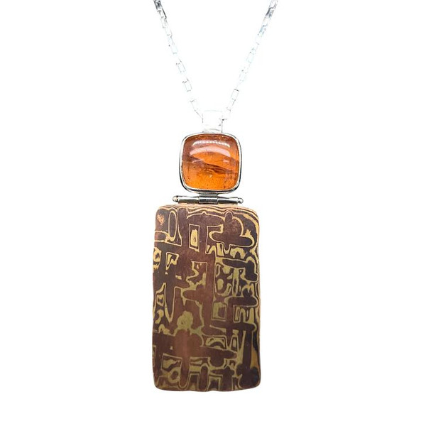 Mokume Gane Pendant with Garnet.
A new jewelry design for me, I hand forged and patterned this mixed metal pendant of copper and brass. This ancient Japanese sword  technique involves fusing 21 layers of alternating metals and hammering patterns to create unique patterns in metal. A very lengthy and involved process rewards us with unique patterns and colors in metal. I cut the spessartite garnet from a crystal from Kenya. It has a nice burnt orange hue that complements the metal colors beautifully. Hinged construction allows the pendant to swing freely and includes an 18” sterling silver chain. 2”L x ½ “ W