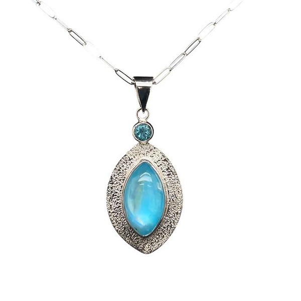 Blue Rainbow Moonstone and Apatite Pendant.
I constructed this unique stone by layering a high quality rainbow moonstone from Madagascar onto a thin sheet of blue turquoise from Persia. The intense blue color shines though. Matched with a faceted Apatite accent from Madagascar. When worn, the moonstone exhibits adularescence which creates a blue sheen that moves across the stone. Very unique. Hand textured sterling silver and 18” silver chain included.