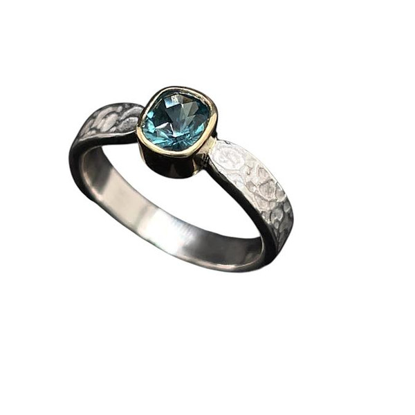 Tourmaline Ring in Gold and Silver. I cut this high quality Afghan tourmaline in a design called ‘Turtle Checker’ with over 70 facet cuts. It’s a unique design with a diamond checkerboard design cut on the table. Beautiful Indicolite tourmaline crystal at 0.8 ct in set in an 18K gold bezel. Ring shank is textured sterling silver in a size 6 ¾  ring.