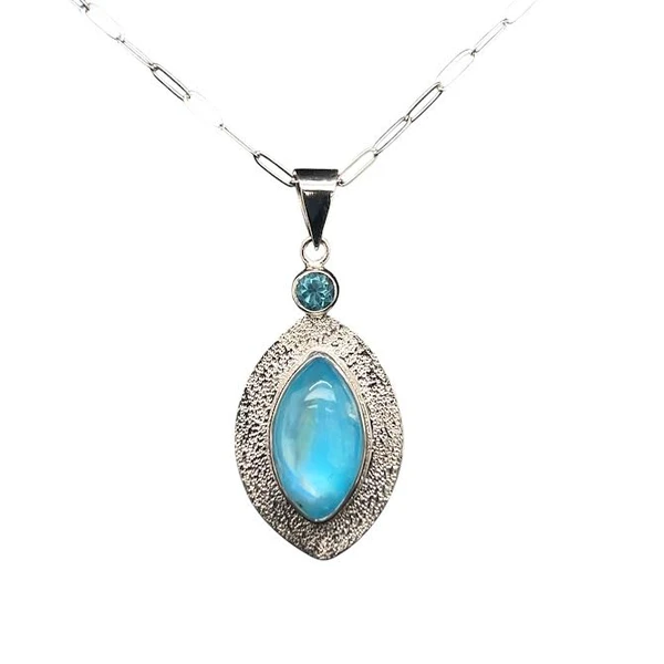 Blue Rainbow Moonstone and Apatite Pendant.
I constructed this unique stone by layering a high quality rainbow moonstone from Madagascar onto a thin sheet of blue turquoise from Persia. The intense blue color shines though. Matched with a faceted Apatite accent from Madagascar. When worn, the moonstone exhibits adularescence which creates a blue sheen that moves across the stone. Very unique. Hand textured sterling silver and 18” silver chain included.