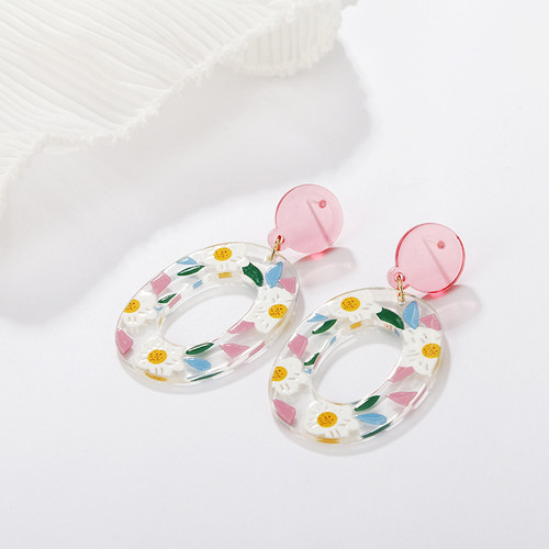 hollow oval acrylic earring with pastel colour floral daisy pattern hung from pink round stud with posts