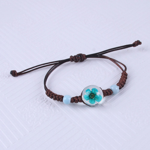 Bracelet with blue dried flower in glass bead on brown cord