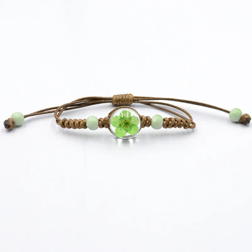 Bracelet with green dried flower in a glass ball on brown cord