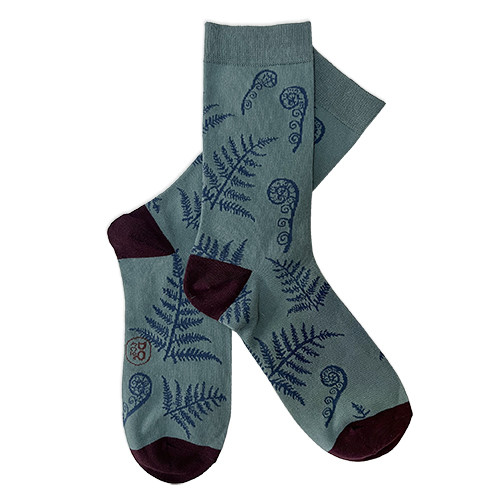 Pair of teal NZ souvenir socks with silver fern and koru motifs and dark heels and toes