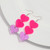 rop of two neon pink hearts and one glittery heart earrings on hook”