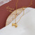 Delicate gold colour chain necklace with bow pendant and bead detail