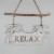 White hanging wooden sign with palm trees and "Relax"