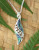 Angel's wing shaped sterling silver pendant with cut-out koru pattern and NZ paua shell inlay