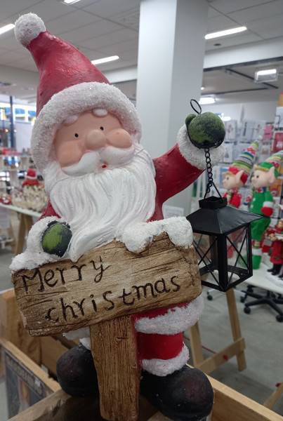 Standing Santa holding a lantern and Merry Christmas sign