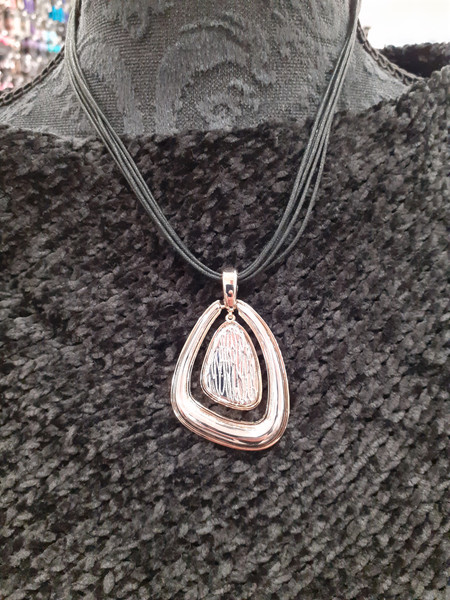 Silver and gold coloured pendant on black cord necklace