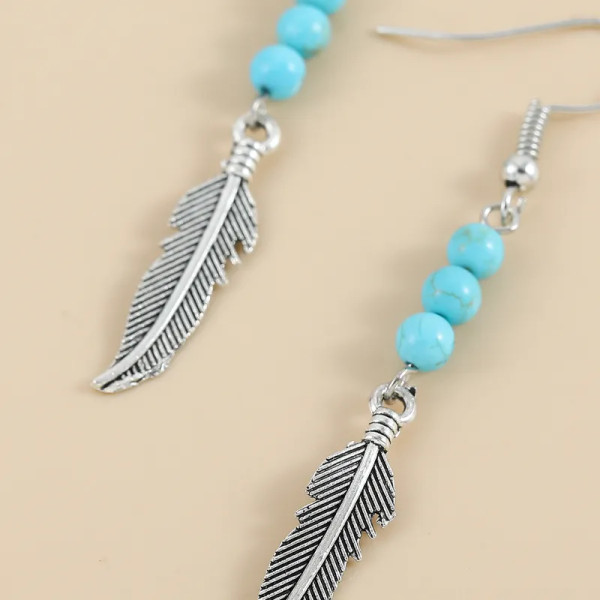 silver coloured feather with turquoise coloured bead earrings on hook