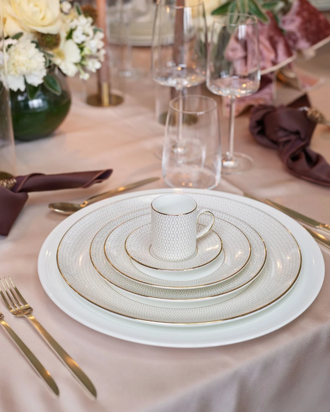 Close-up of layered Wedgwood Gio Gold plates with Victoria Gold cutlery