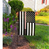 Black and white American flag, the word NURSE is embroidered over a red line on a garden pole in front of a house.