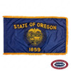 The indoor Oregon flag has 3 sides of gold fringe around the dark blue field. In the center is the state seal & the text “State of Oregon 1859”. FMAA Certified Made in America seal.