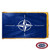 The indoor NATO flag has 3 sides of gold fringe around a dark blue field with a white compass rose in the center. FMAA Certified Made in America seal.