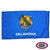 The blue Oklahoma flag has an Osage shield in the center, adorned with feathers, a calumet, & an olive branch. The text “Oklahoma” is below. FMAA Certified Made in America seal.