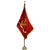 The flag of the U.S. Marine Corps features a centered gold eagle, gray globe, and gold anchor, the Corps’ traditional logo, with a streaming banner beneath reading “United States Marine Corps” all over scarlet background. It hangs at rest, attached to an ornate golden flagpole. The flag’s sides not attached to the flagpole have golden fringes. A decorative gold cord and tassel sit at the top of the flagpole.