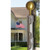 The T20 20’ Telescoping Flagpole stands in front of a house with an American flag sitting atop it. In the photo’s foreground is a close-up shot of the top of the flagpole, showing the gold-painted aluminum decorative ball, the flagpole’s polycarbonate cap, and halyard snaps for easy attachment to your flagpole.