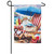 This flag features a scene of two white cats sitting on a beach chair on the beach. They are wearing floppy hats. There is a blue sun umbrella, beach ball, seashells, cocktails, and sand buckets.