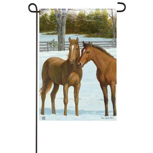 This garden flag features two chestnut horses snuggling together in a winter landscape.