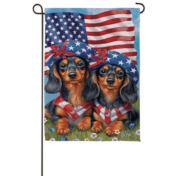 A Patriotic Dachshund Duo Suede Garden Flag depicting two dachshunds wearing American flag scarves and hats, with an American flag in the background.