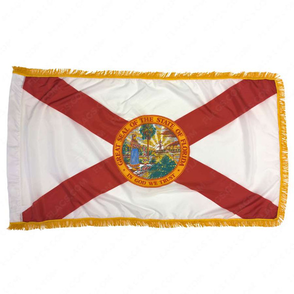 The indoor Florida flag has 3 borders of gold fringe around the white field. There is a red saltire across the flag with a seal in the center.