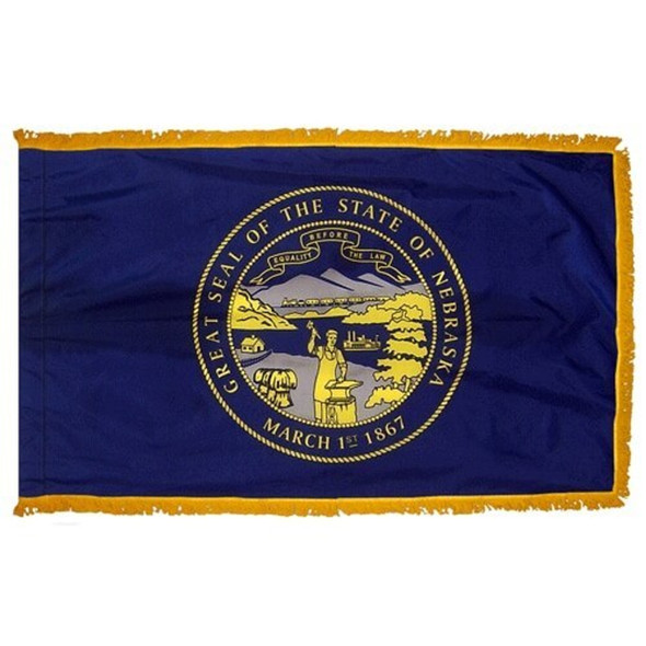 The indoor Nebraska flag has 3 sides of gold fringe around the dark blue field. In the center is the yellow state seal, depicting a blacksmith.