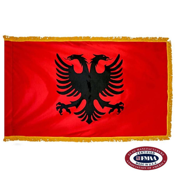 The indoor Albania flag has 3 edges of gold fringe around a red field, in the center of which is a black, double-headed eagle. FMAA Certified Made in America seal.