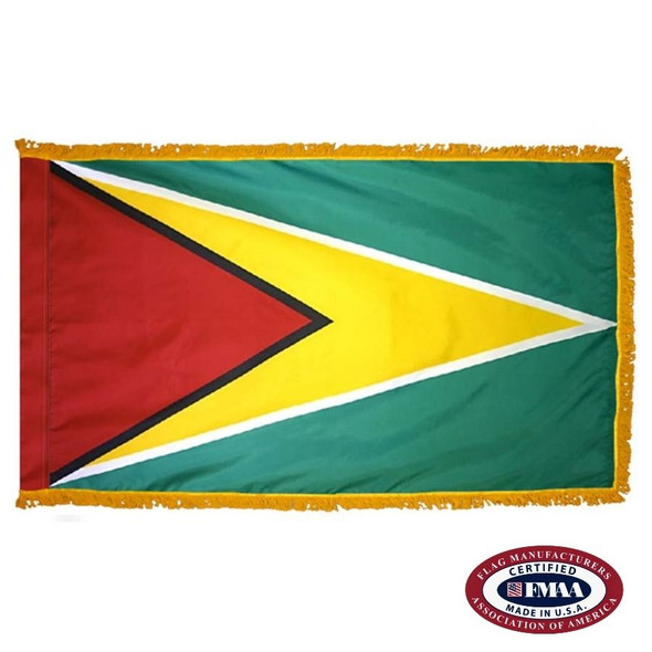 The indoor Guyana flag has 3 sides of gold fringe around a green field with a yellow triangle with a smaller red triangle inside pointing to the right. FMAA Certified Made in America seal.