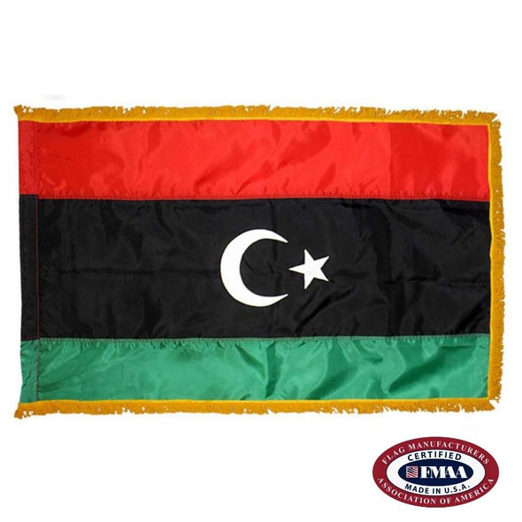 The indoor Libya flag has 3 sides of gold fringe around a red, black, and green tricolor. In the wide black stripe is a crescent and star. FMAA Certified Made in America seal.