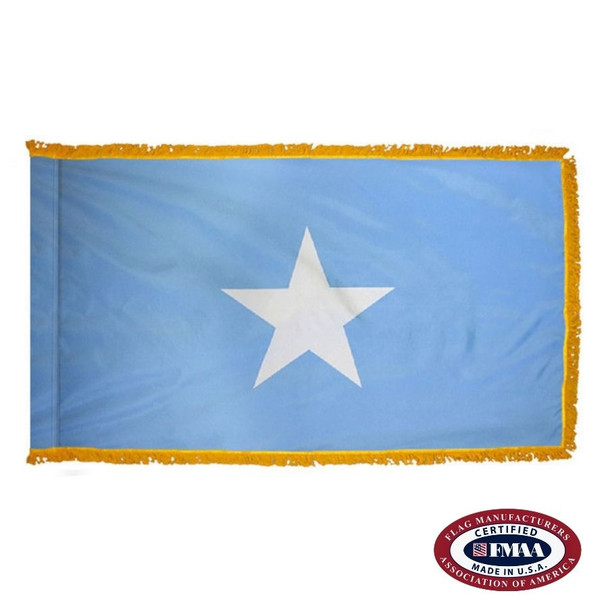 The indoor Somalia flag has 3 sides of gold fringe around a light blue field with a large white 5-pointed star in the center. FMAA Certified Made in America seal.