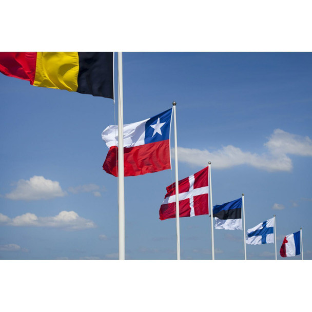 6 outdoor flagpoles flying the flags of Belgium, Chile, Norway, Estonia, Finland, and France from left to right.