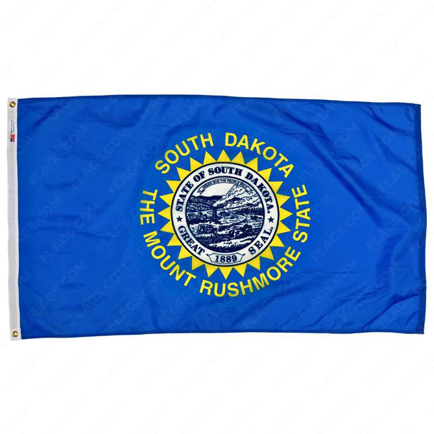 The blue South Dakota flag has a seal in the center, encircled by a serrated border & the text “South Dakota The Mount Rushmore State.”