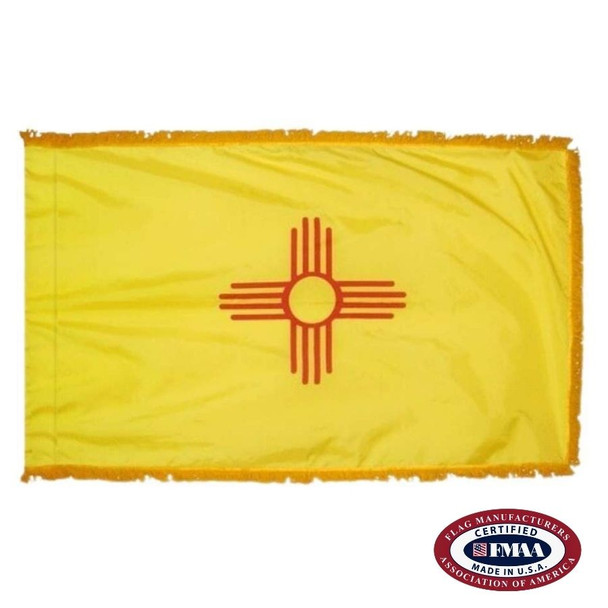 The indoor New Mexico flag has 3 sides of gold fringe around the yellow field. In the center is a red sun symbol.  FMAA Certified Made in America seal.