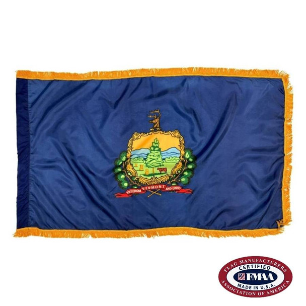 The indoor Vermont flag has 3 sides of gold fringe around the dark blue field. In the center is a seal depicting a cow & hay under a tree. FMAA Certified Made in America seal.