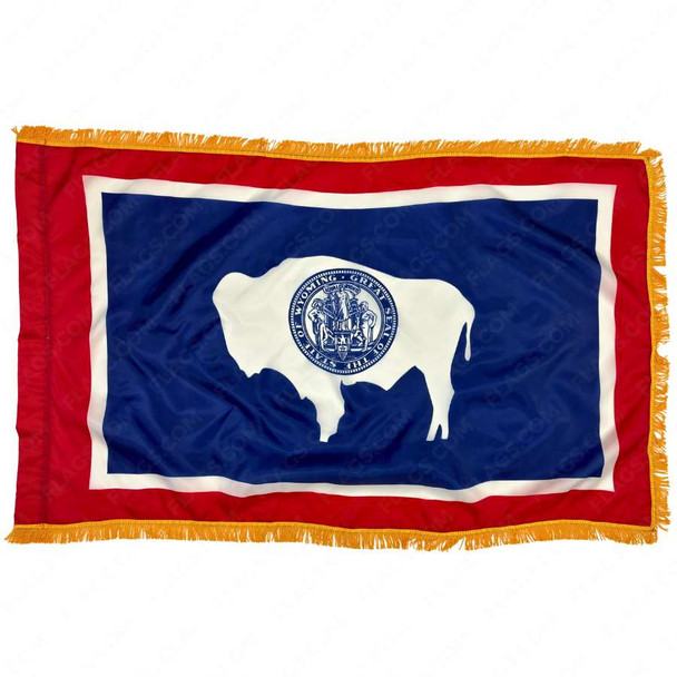 The indoor Wyoming flag has 3 sides of gold fringe around the red and white-bordered blue field. In the center is a bison and state seal.