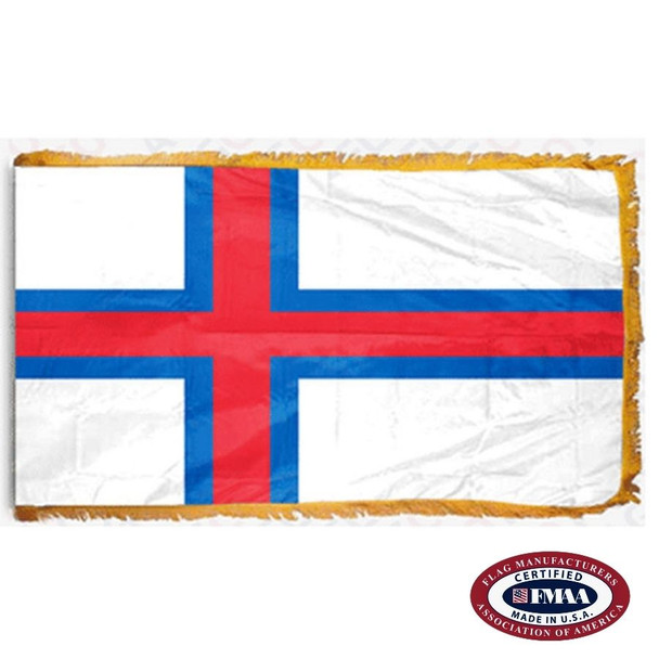 The indoor Faroe Islands flag has 3 sides of gold fringe around a white field with a red cross with a blue outline pointing to the left. FMAA Certified Made in America seal.