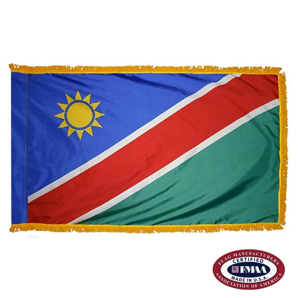 The indoor Namibia flag has 3 sides of gold fringe around blue & green fields separated by a diagonal red line with a sun in the upper left. FMAA Certified Made in America seal.