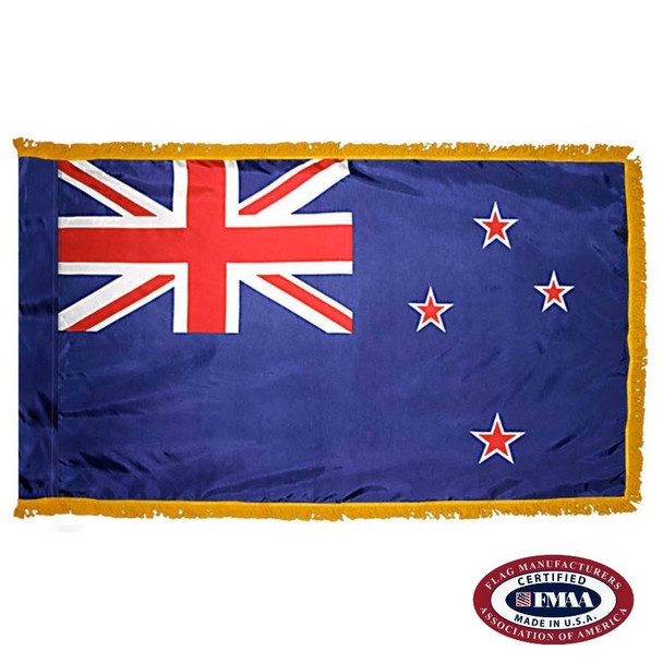The indoor New Zealand flag has 3 sides of gold fringe around a blue field with the Union Jack in the canton and 4 red stars on the right. FMAA Certified Made in America seal.